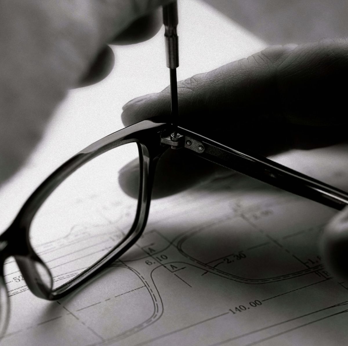 Person adjusting eyeglasses with a screwdriver on a technical drawing background